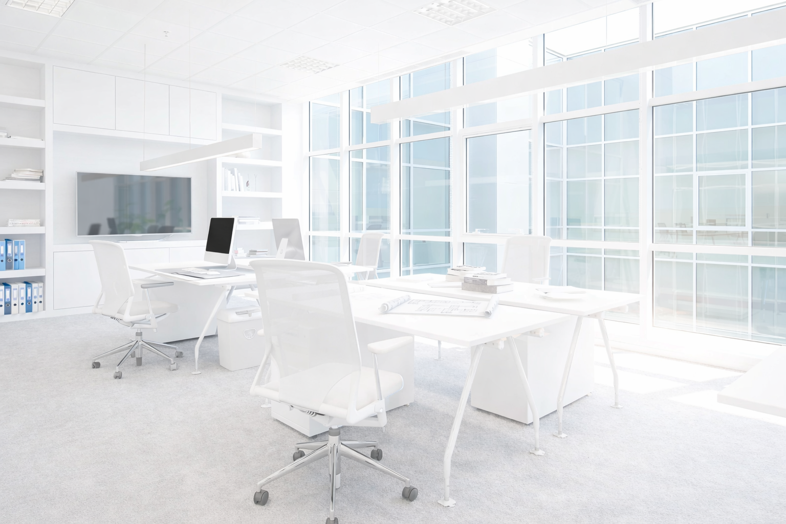 Bright white office space with desks, chairs, and large windows. Includes a flat screen TV and shelving.