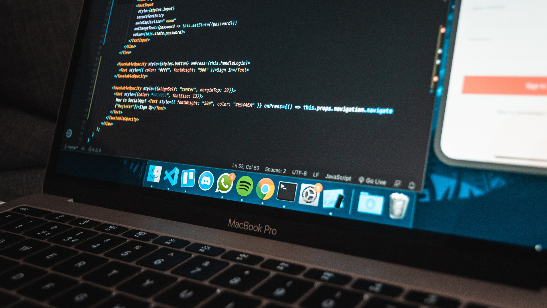 Laptop displaying code with phone visible.