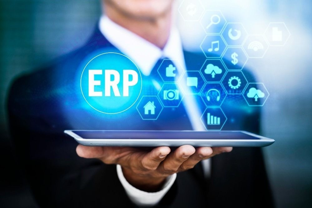 Businessman holding tablet with glowing ERP logo and tech icons.