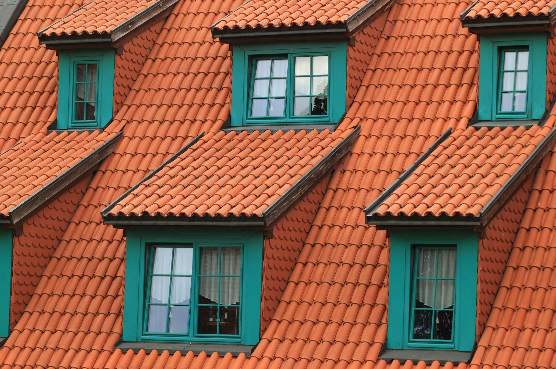 Red tiled roof with teal window frames.