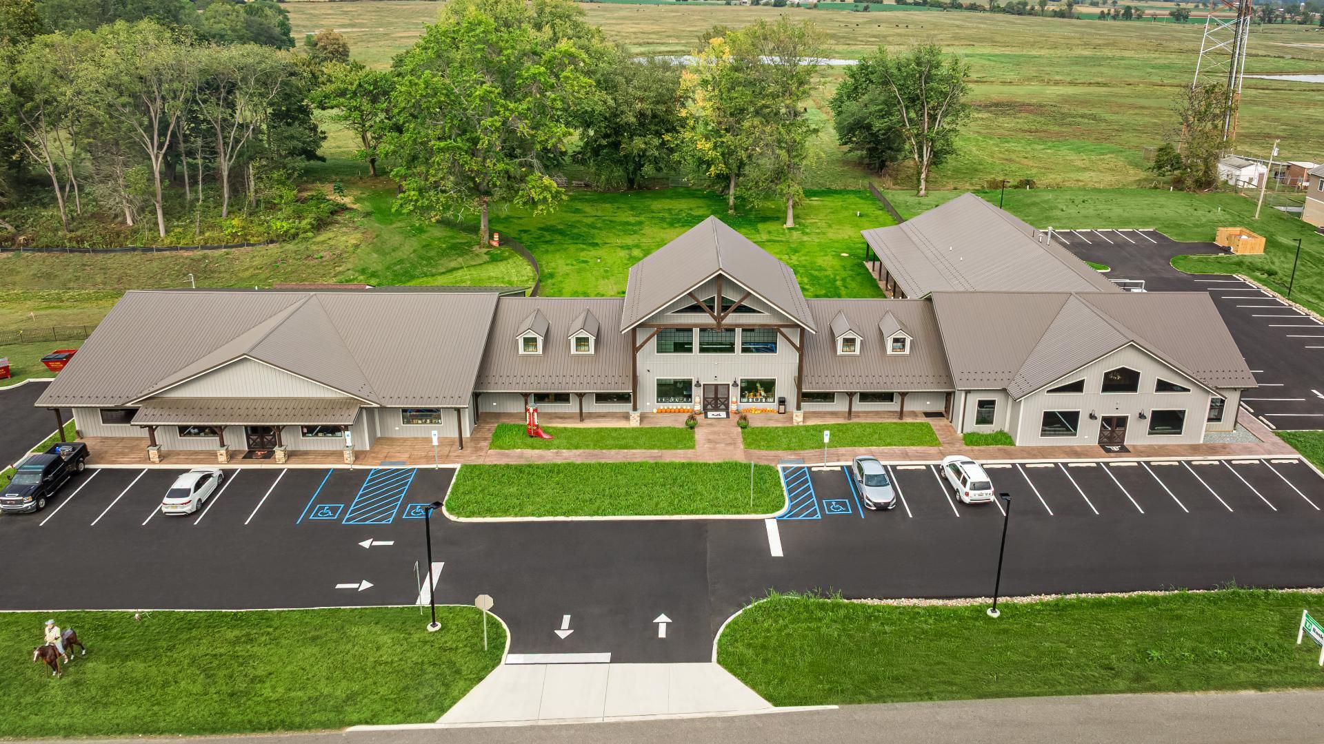 An aerial view of Bullhide Brewery in Pilesgrove, NJ, showing the parking lot, front facade, and roof of the structure. 