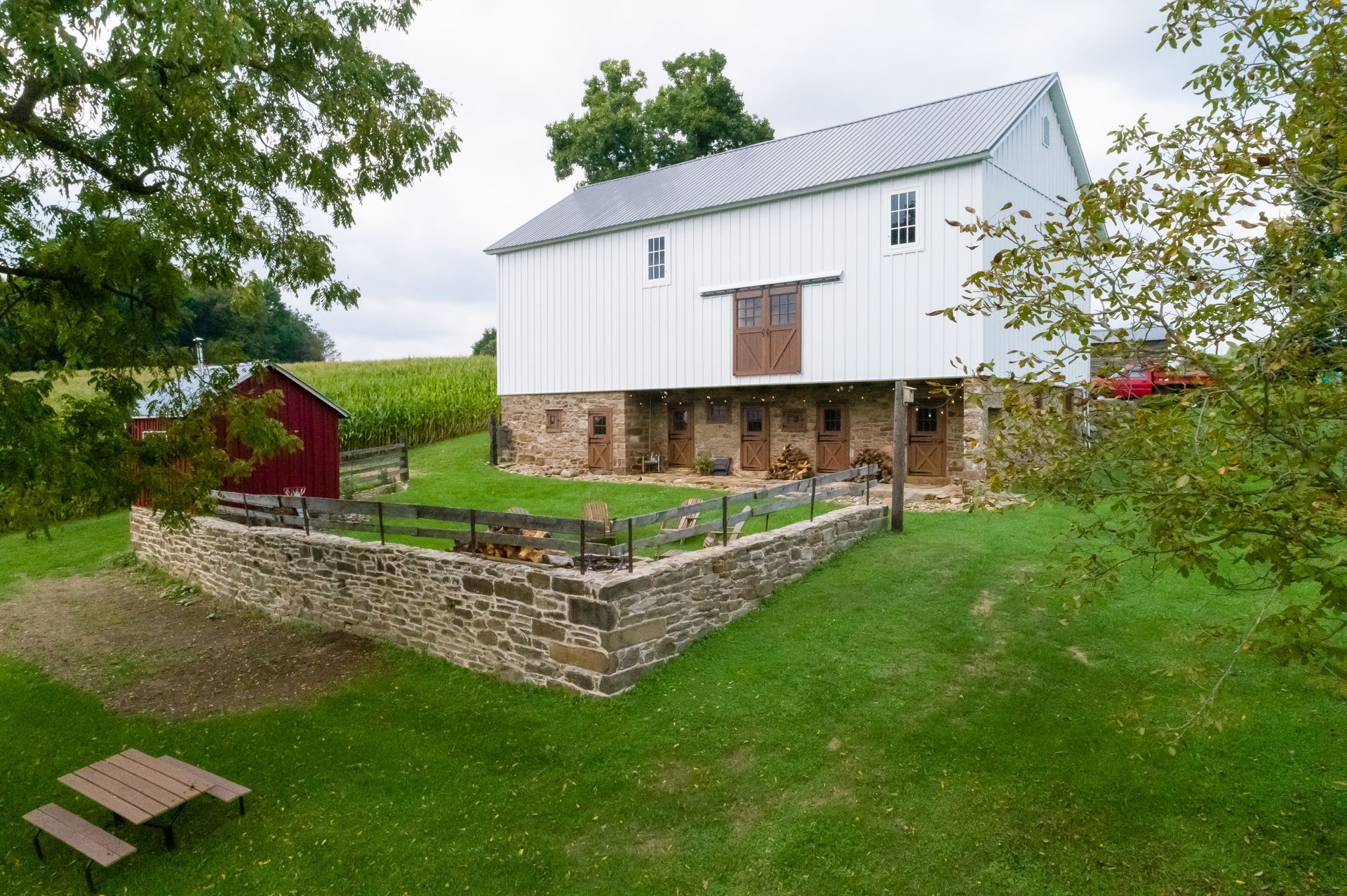 Red bank barn with black metal roof, 5 black garage doors, and lighted interior 