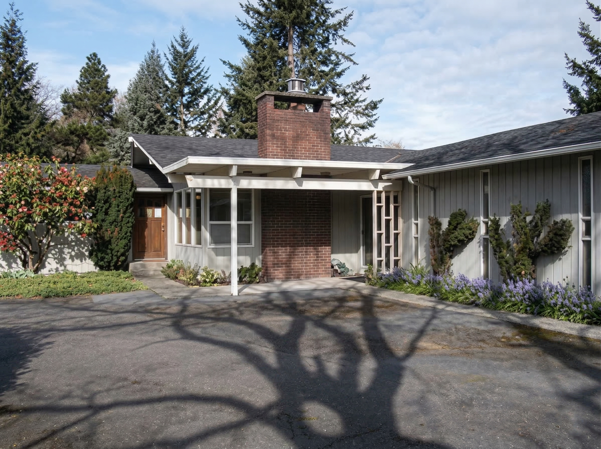 The front door of a house with a porch and plants in front of it.