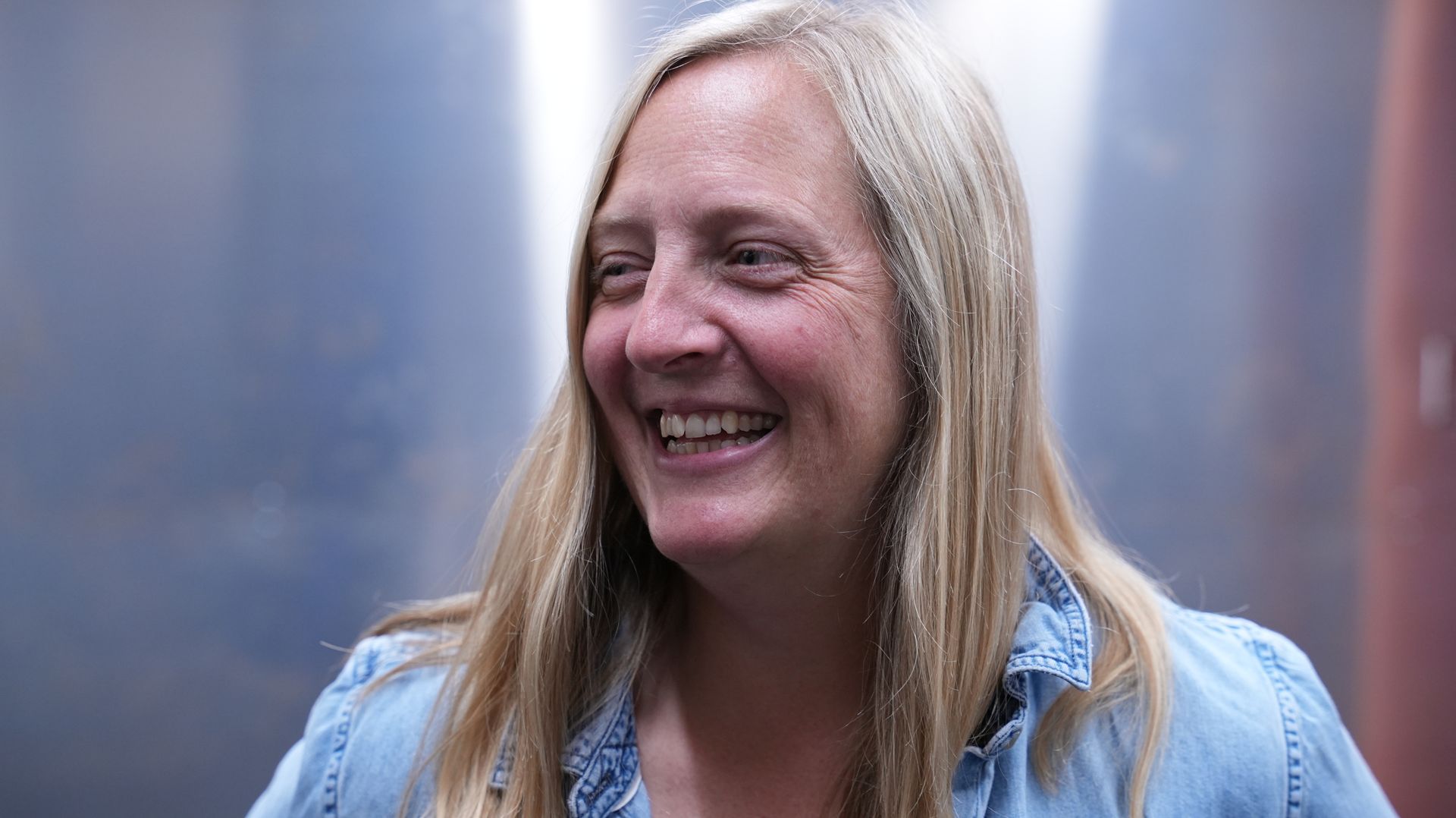 Atlas operations manager Sara, a woman with long blond hair and wearing a blue shirt, is smiling for the camera.