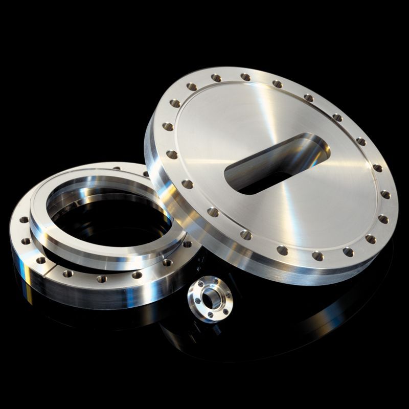 Three aluminum/stainless bimetal flanges of different sizes, one rotatable, one used for beamlines, and one mini, on black.