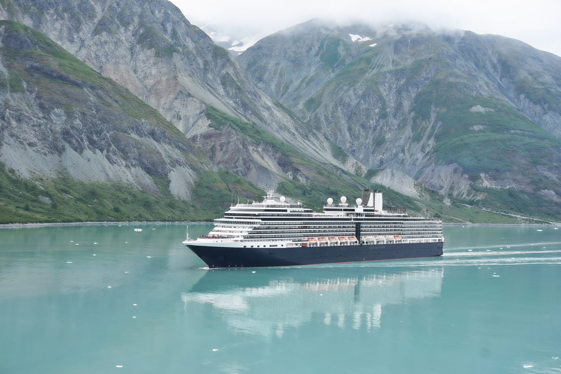 A cruise ship is floating on top of a body of water with mountains in the background.