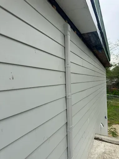 Gray siding with a vertical downspout attached to the side of a building.