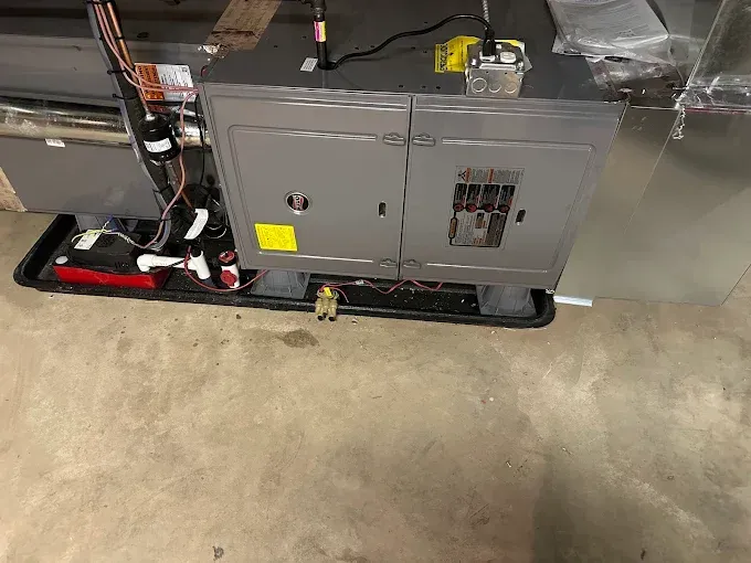 Furnace unit on a black tray, with pipes and wires.