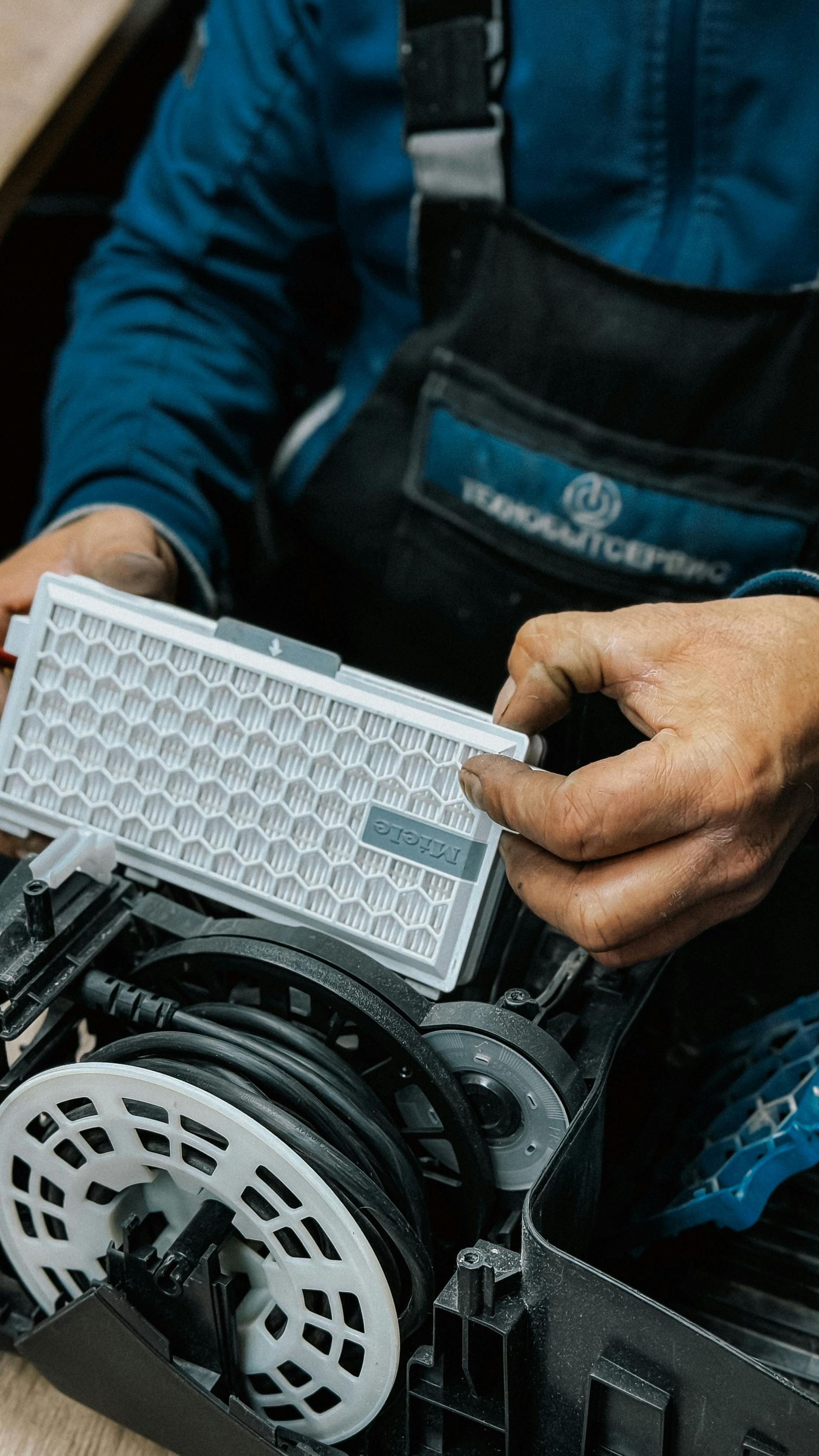 Mechanic holding air filter, working on machinery, close-up, indoors.