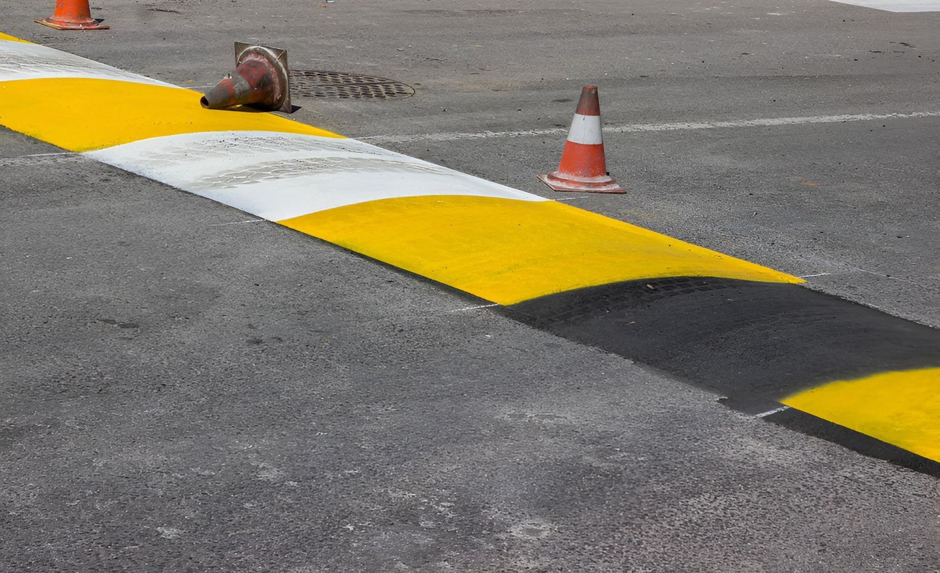 A Yellow and Black Speed Bump With Traffic Cones on the Side of the Road — F & J Bitumen Services in Adelaide River, NT