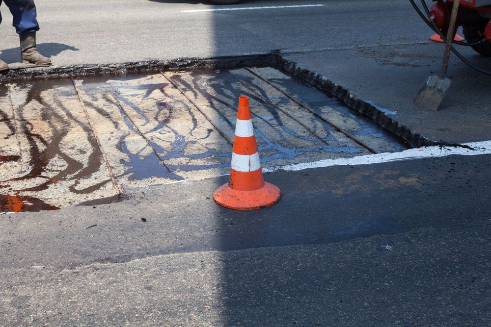 An Orange and White Traffic Cone is Sitting on the Side of the Road — F & J Bitumen Services in Katherine, NT