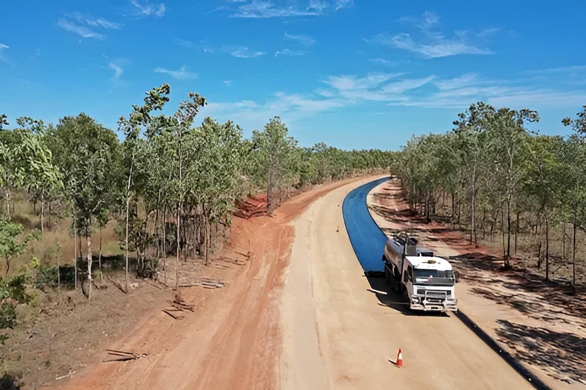An Aerial View of a Truck Driving Down a Dirt Road with Wet Asphalt — F & J Bitumen Services in Humpty Doo, NT