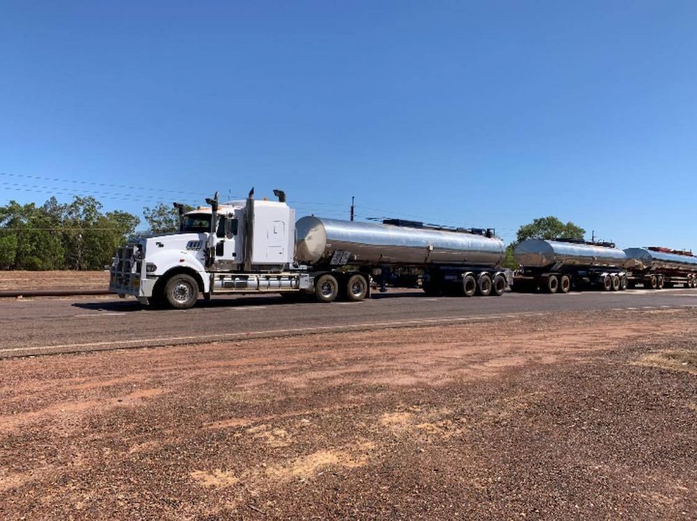 A Large Semi Truck is Driving Down a Dirt Road — F & J Bitumen Services in Humpty Doo, NT