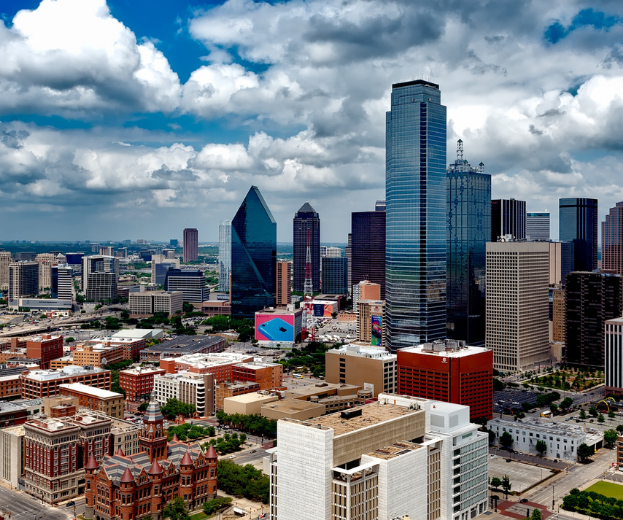 Downtown skyline with tall glass skyscrapers under a cloudy blue sky