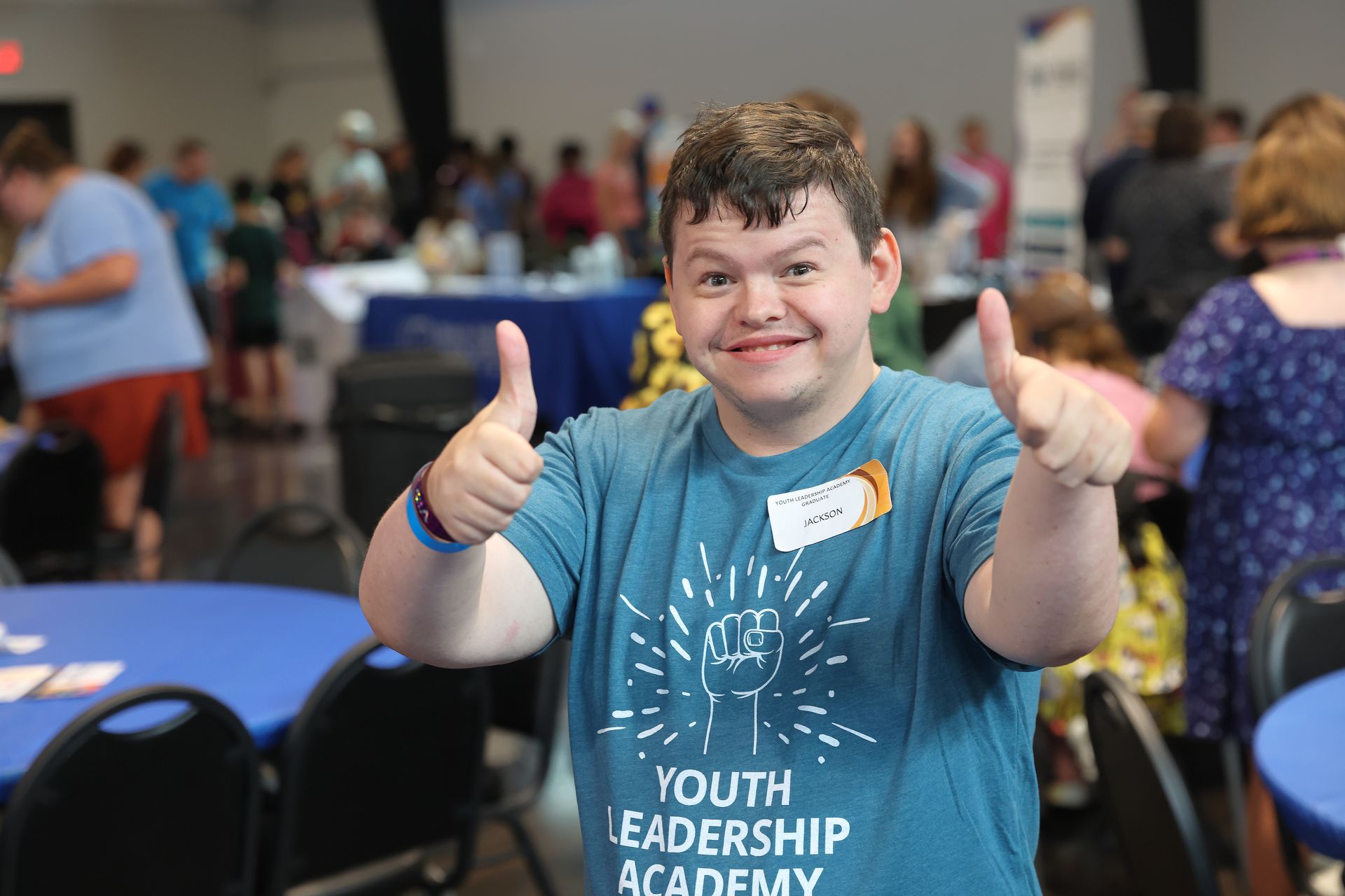 A YLA graduate smiling at the camera and giving a thumbs up with two hands