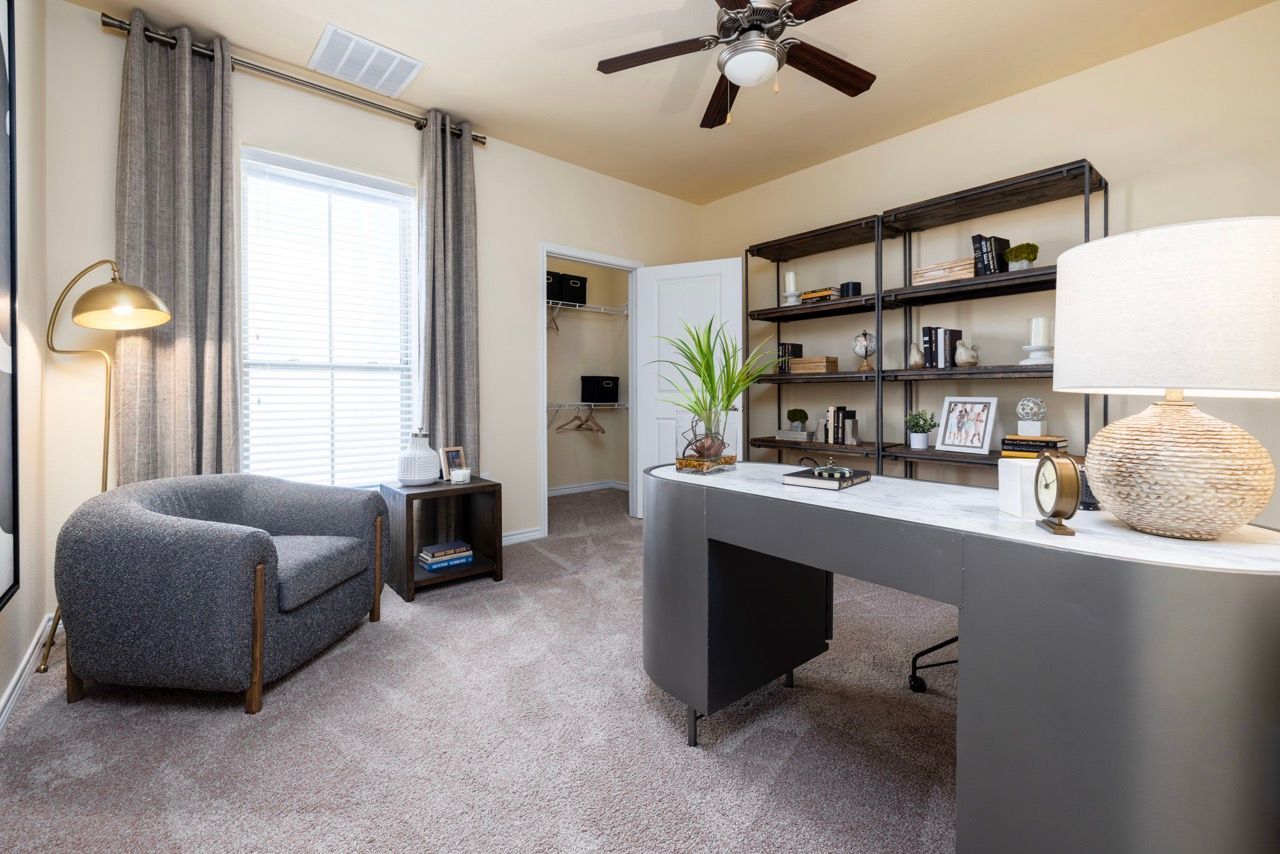 Home office with a marble desk, metal shelving, chair, lamp, and window with curtains.