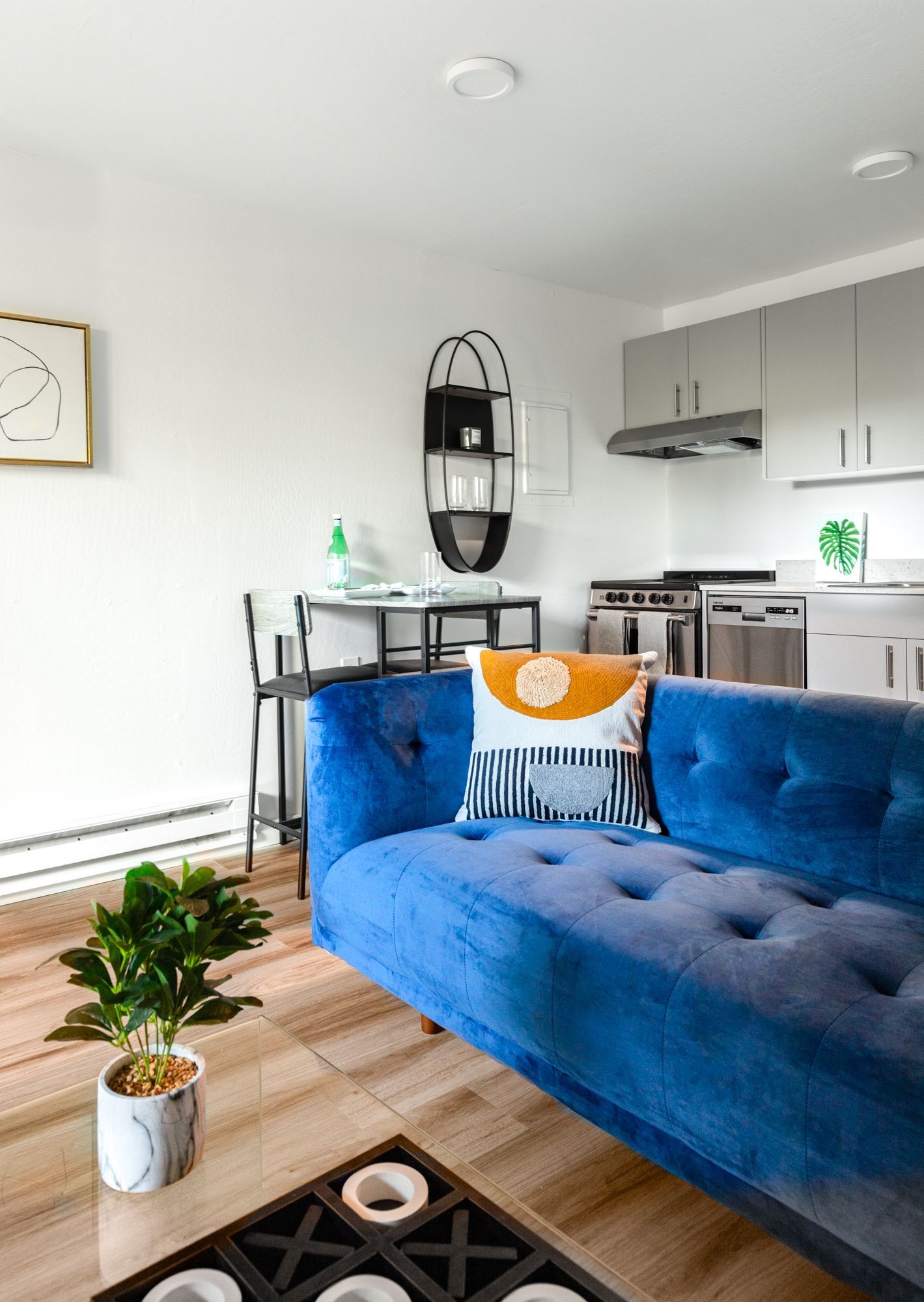 Bright blue sofa in a modern open-plan living room with kitchen and dining area, plus coffee table and plant