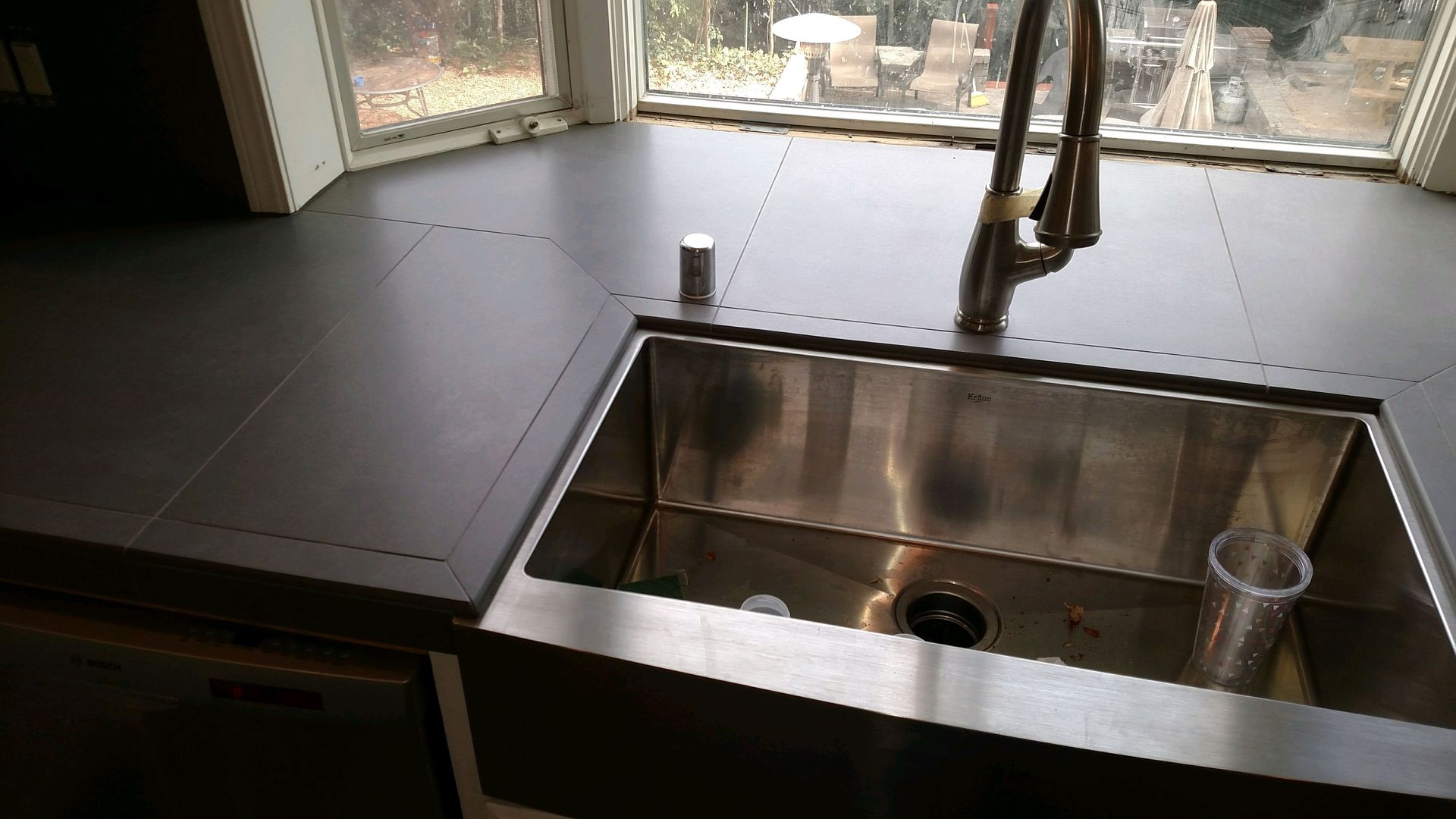 A stainless steel kitchen sink with a window in the background