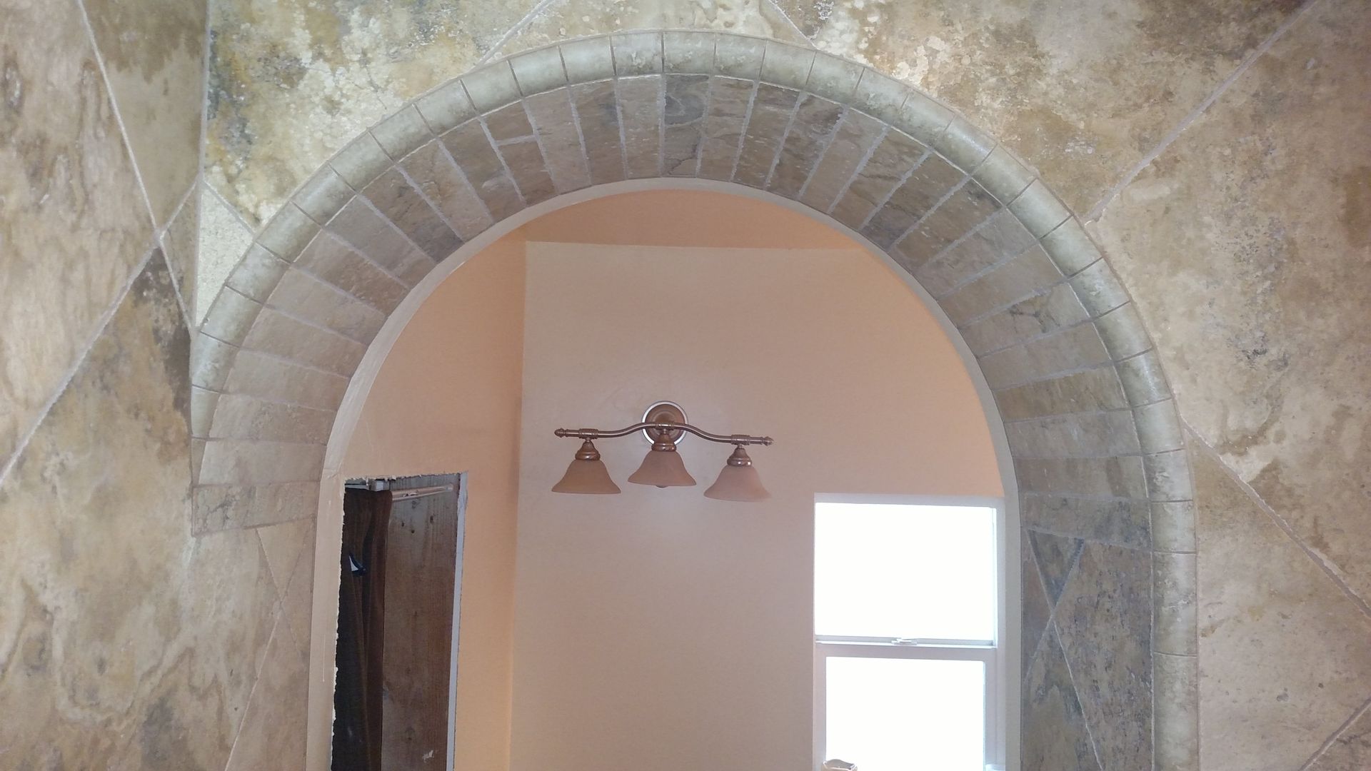 A room with a stone archway and three lights on the wall