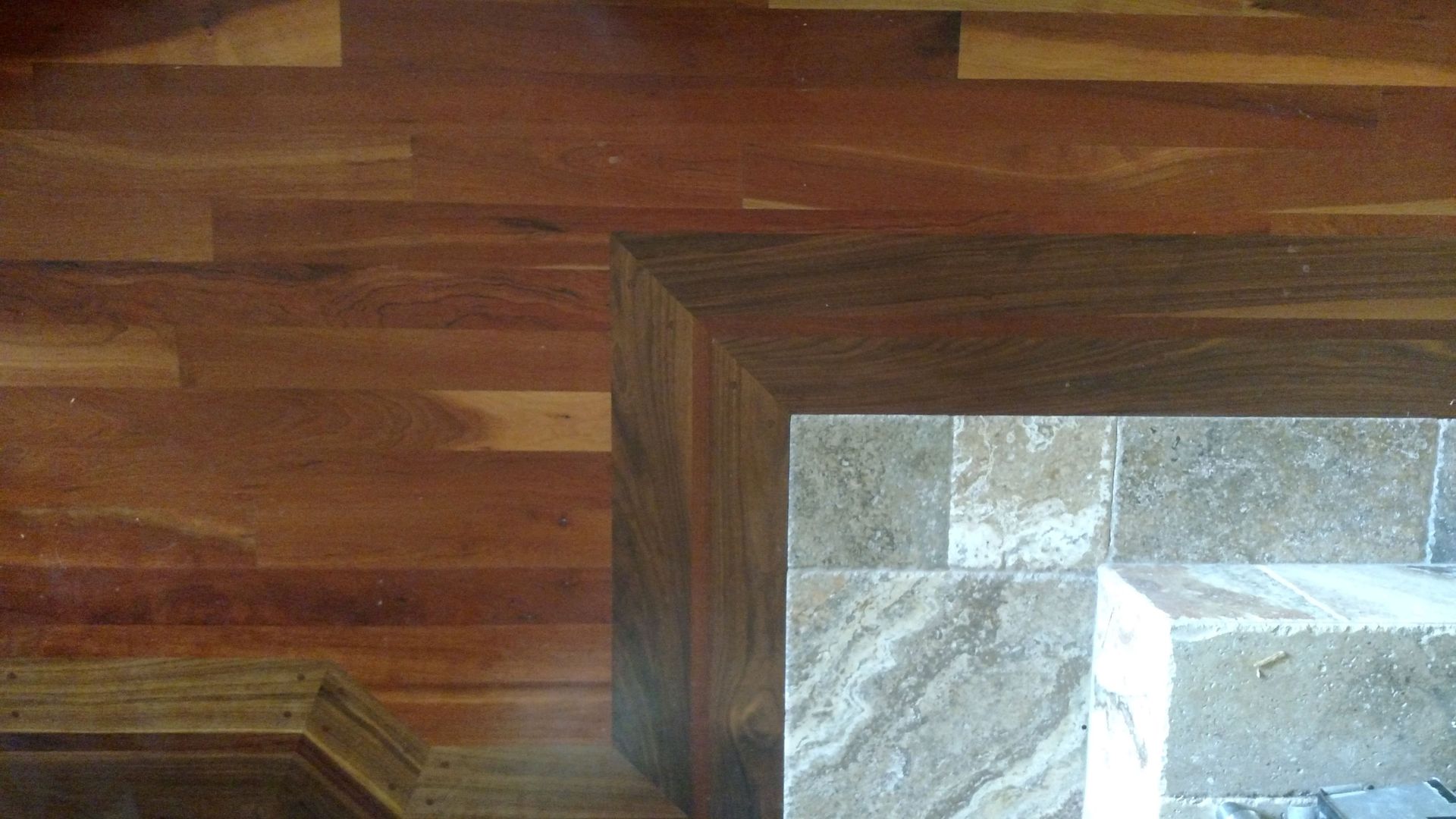 A wooden floor with a marble counter top in the background