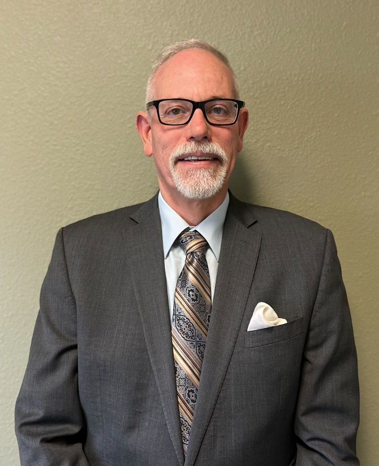 A man in a suit and tie is standing in front of a wall.