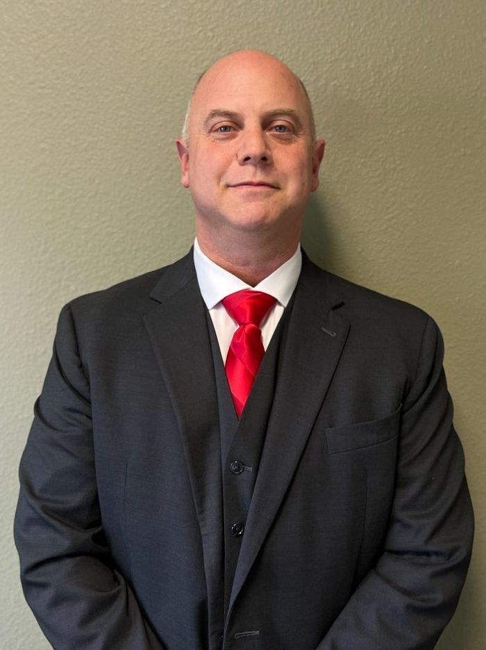 A man in a suit and tie is standing in front of a wall.