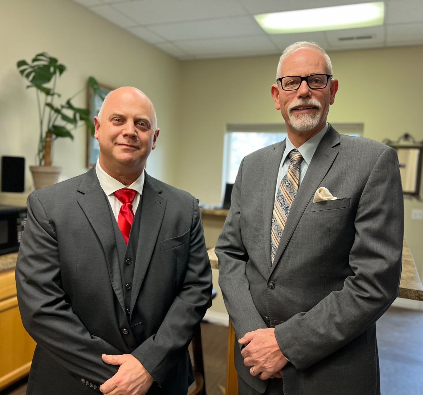 Two men in suits and ties are standing next to each other in a room.