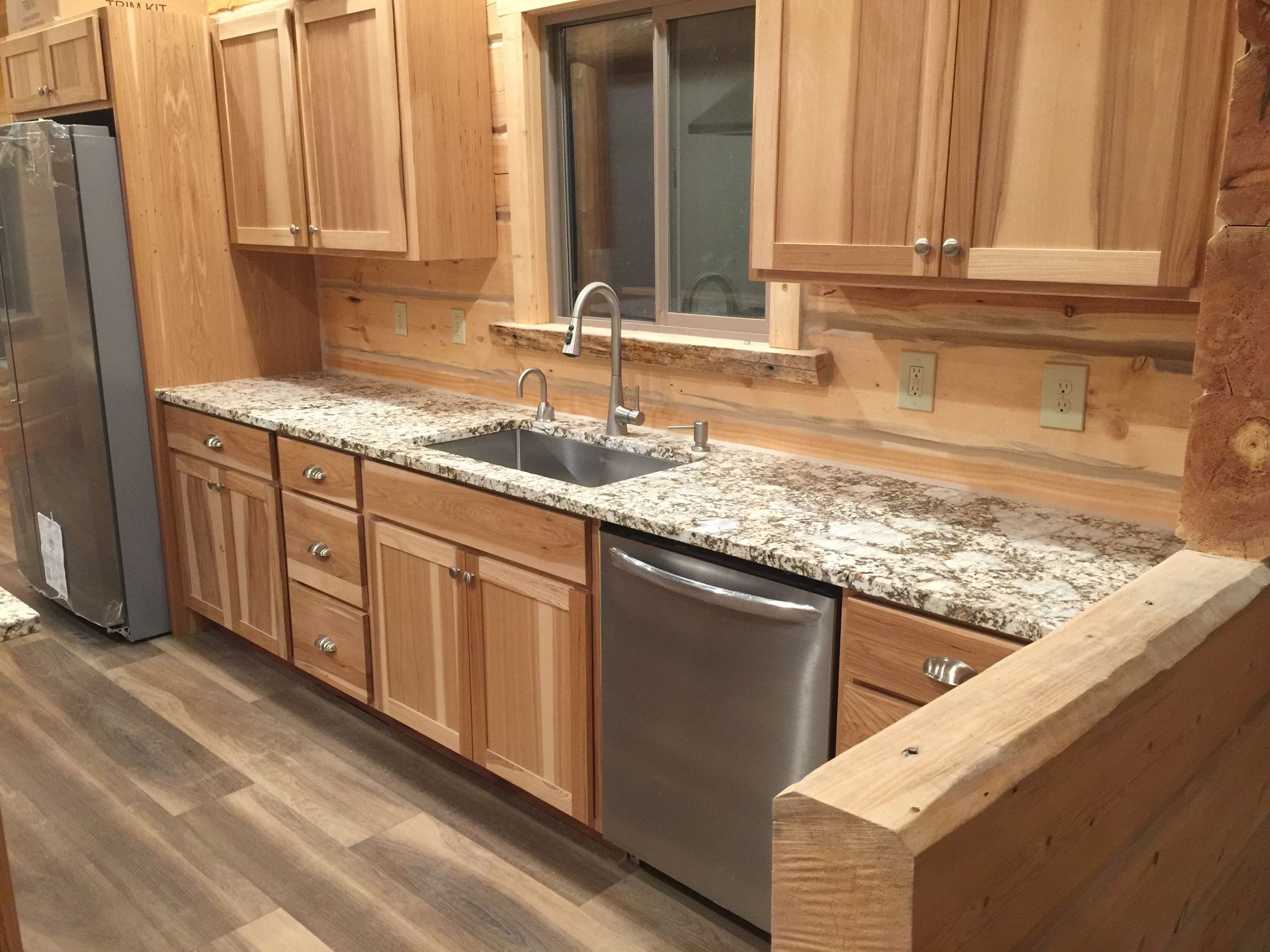 A kitchen with wooden cabinets , granite counter tops , stainless steel appliances and a sink.