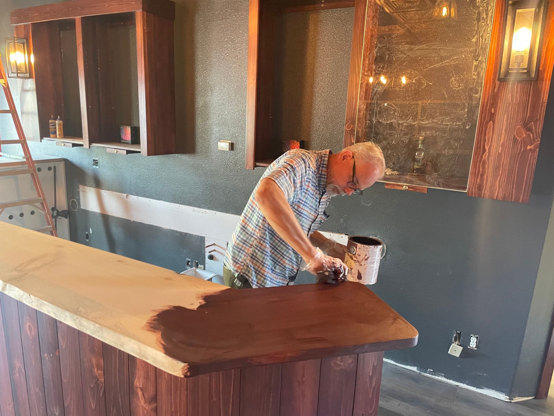 Ed painting a wooden counter in the racketeer lounge