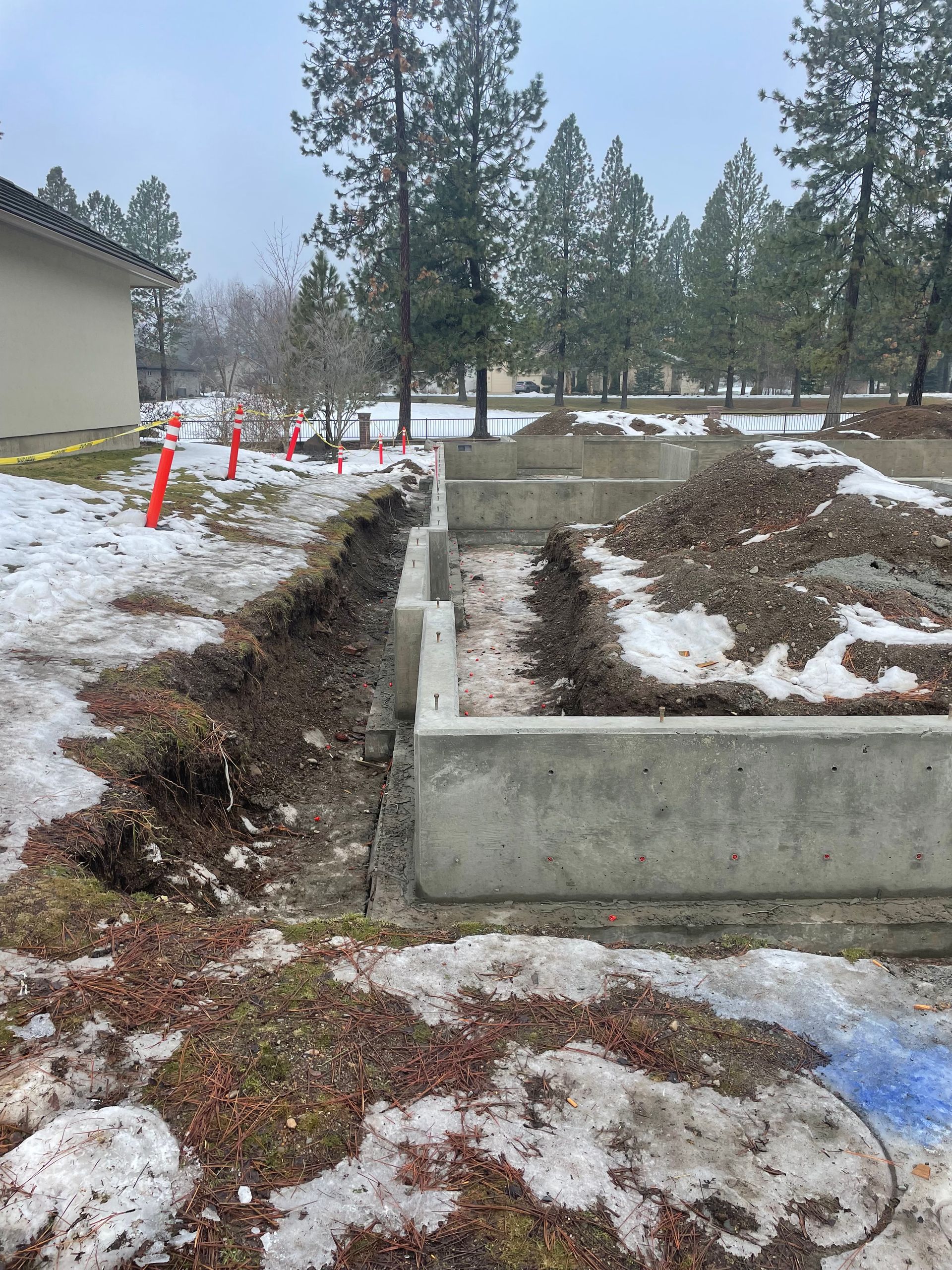 A concrete foundation is being built in the snow in front of a building.