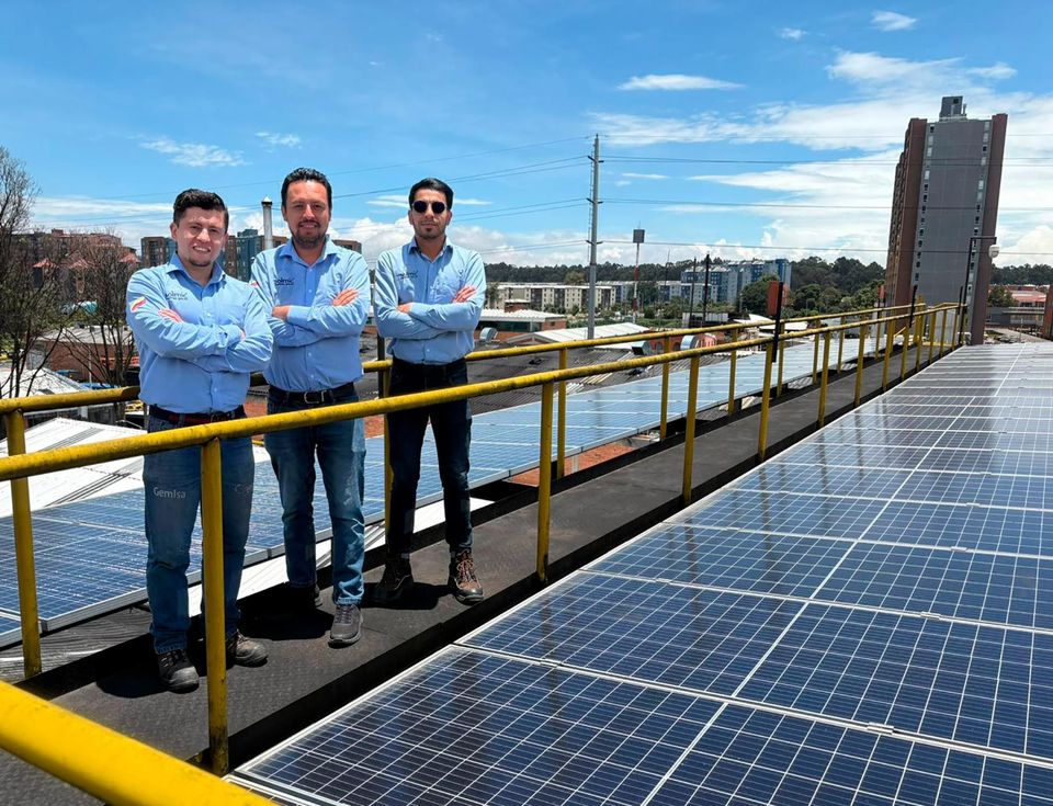 Energía renovable Cuatro personas con cascos y máscaras se encuentran sobre un techo con paneles solares.