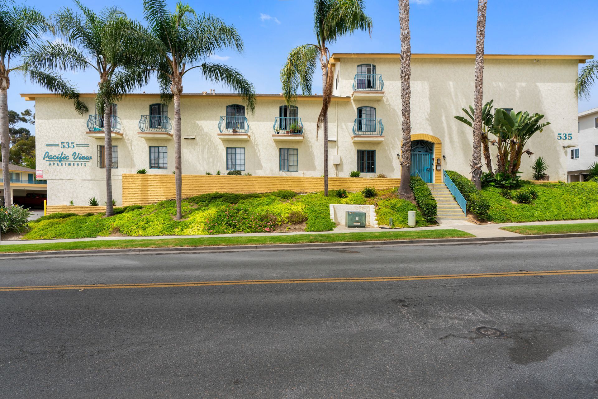 A white apartment building with palm trees in front of it