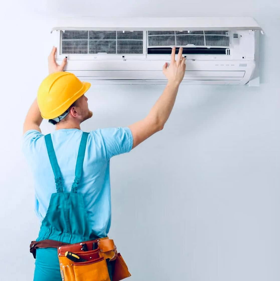 Technician in Yellow Hard Hat Servicing a Wall-mounted AC — A & T Air-Conditioning and Refrigeration in Millbank, QLD