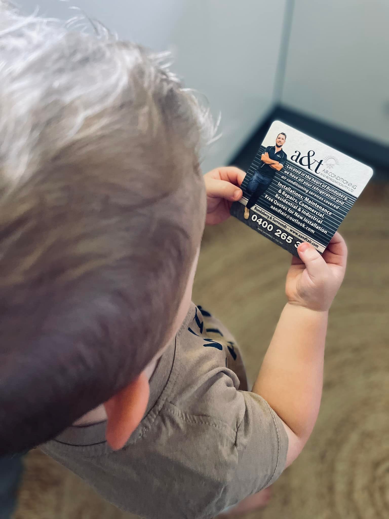 Child Holding a Small Card With Text and a Photo — A & T Air-Conditioning and Refrigeration in Millbank, QLD