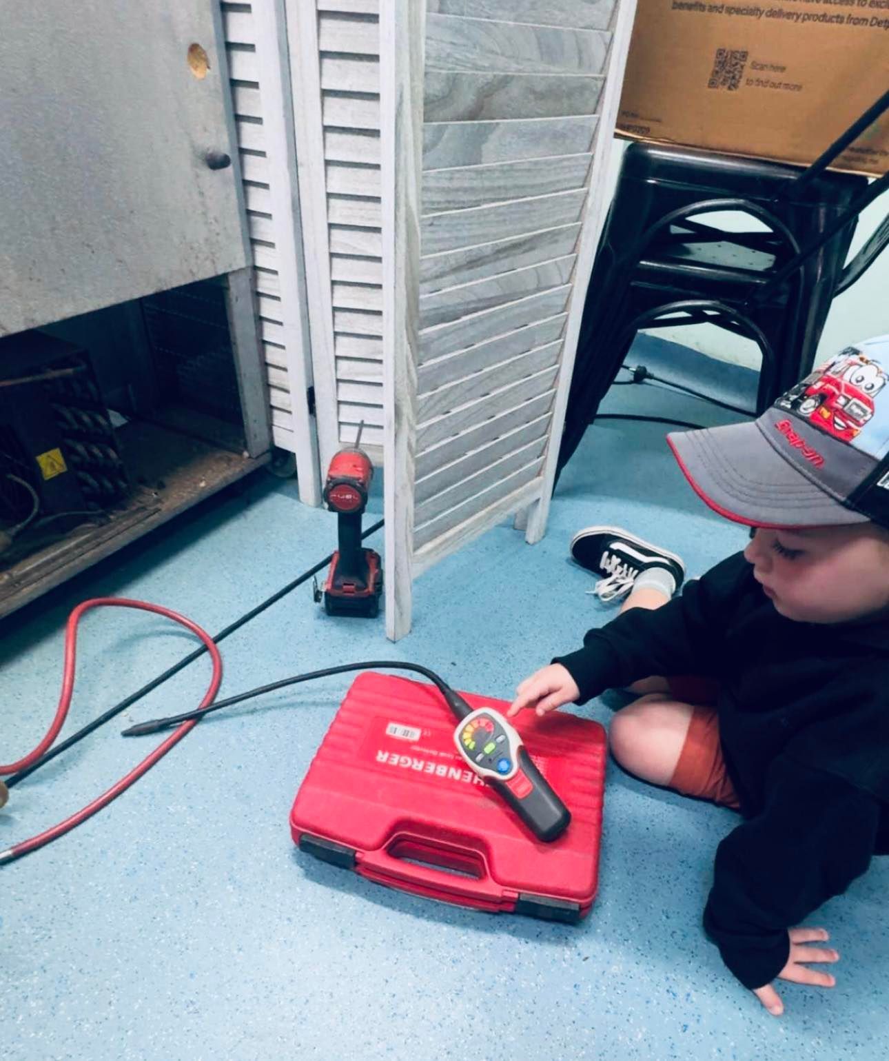 Child Kneeling Beside a Red Toy Case — A & T Air-Conditioning and Refrigeration in Millbank, QLD