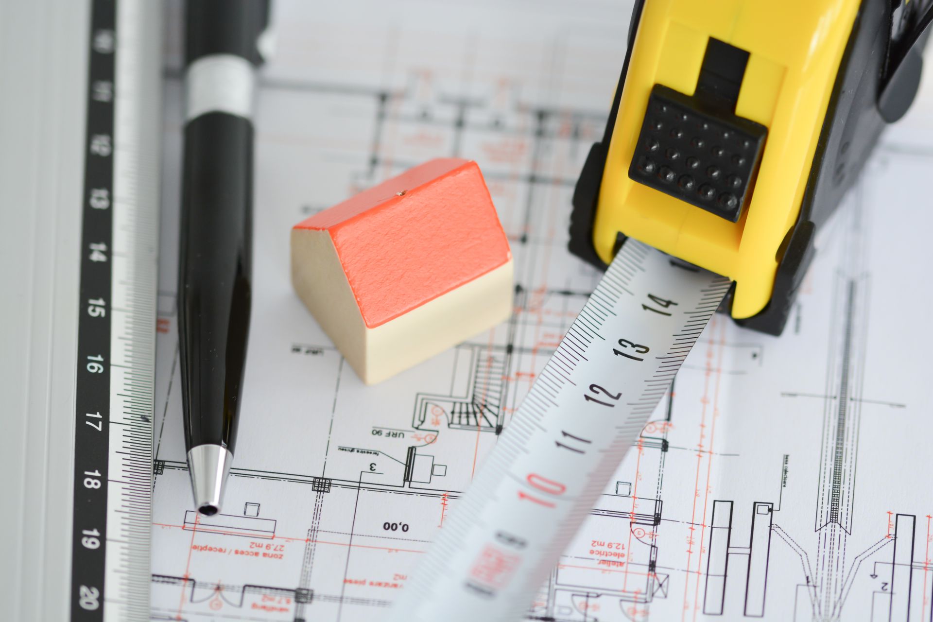 Construction tools over architectural blueprints with pencil, eraser, and tape measure