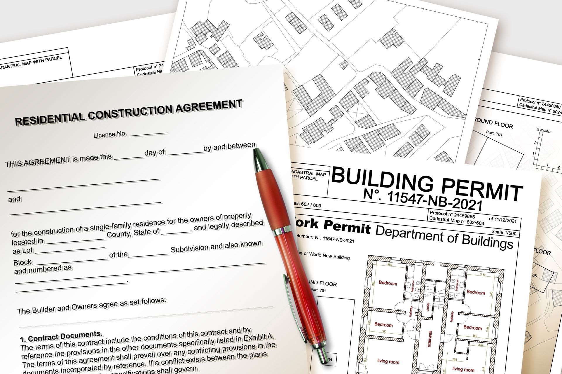 Construction documents and building permit forms with a red pen on a desk