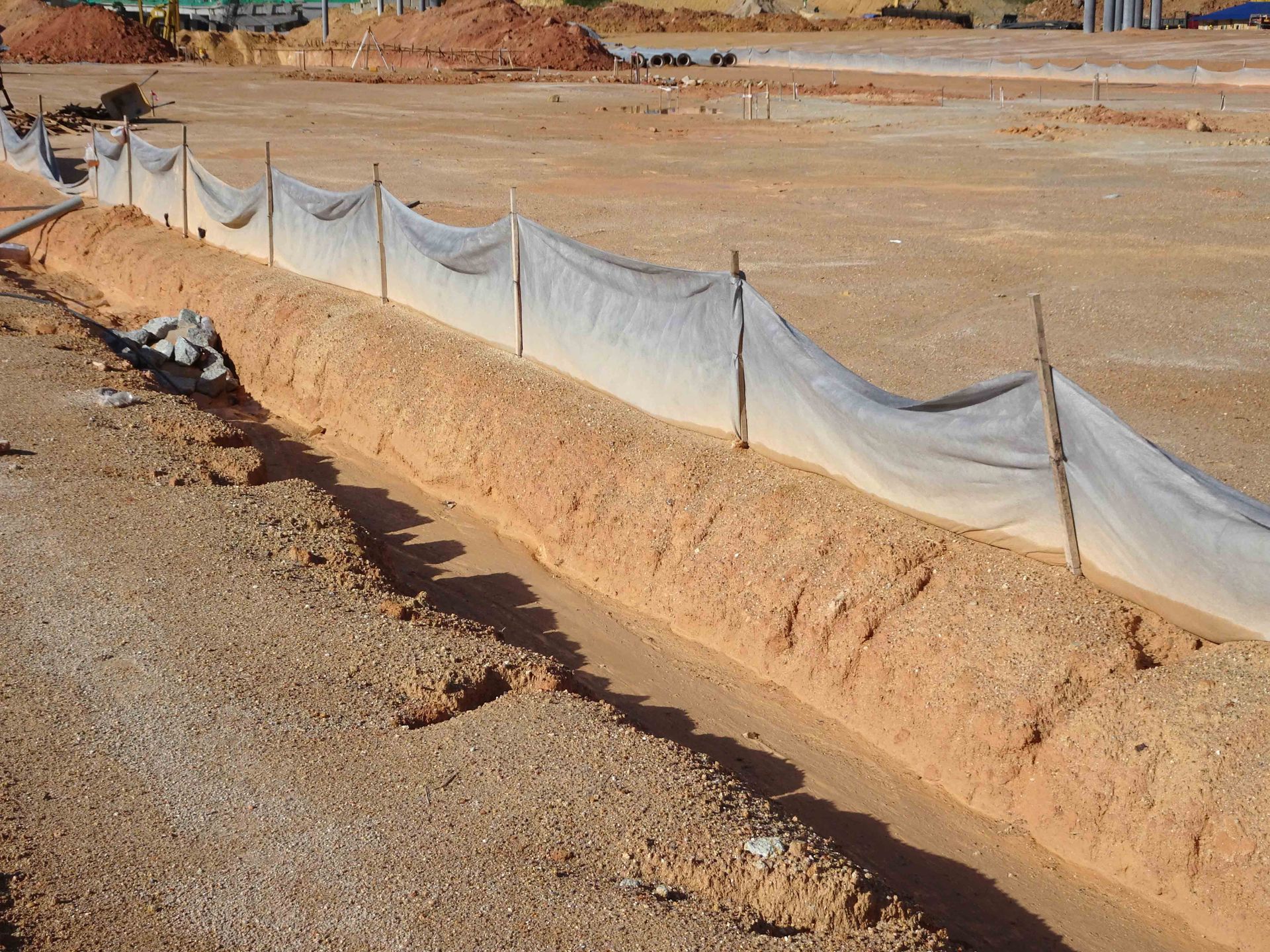 Erosion control barrier lined with white fabric along a dirt construction site trench