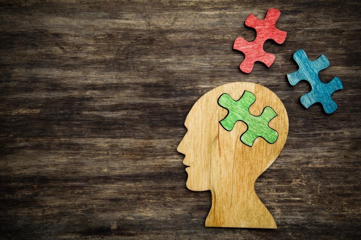 A wooden head with puzzle pieces in it on a wooden table.