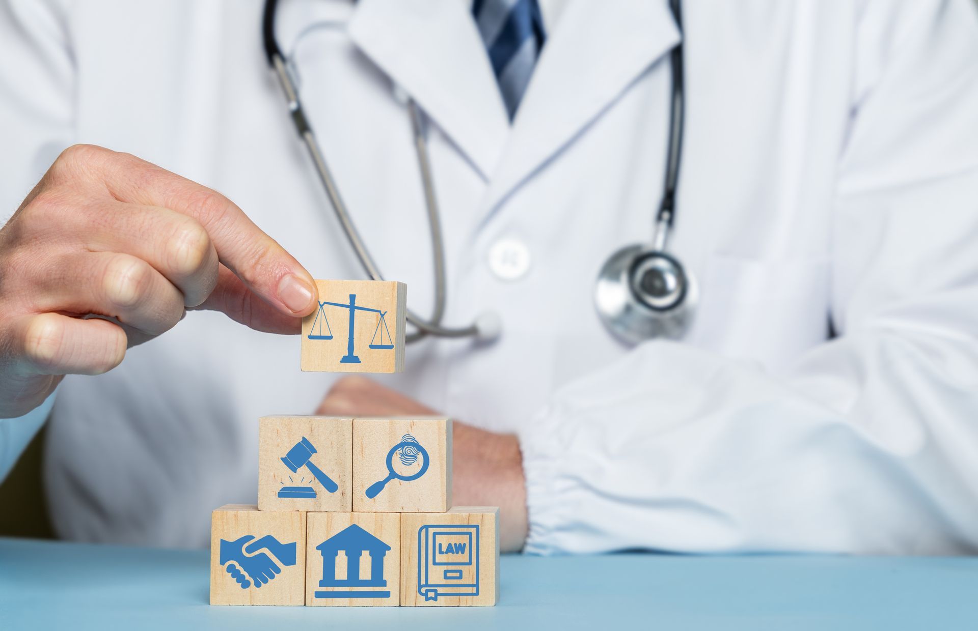 Doctor holding block with law icon over stack of healthcare-related blocks Doctor holding block with law icon over stack of healthcare-related blocks