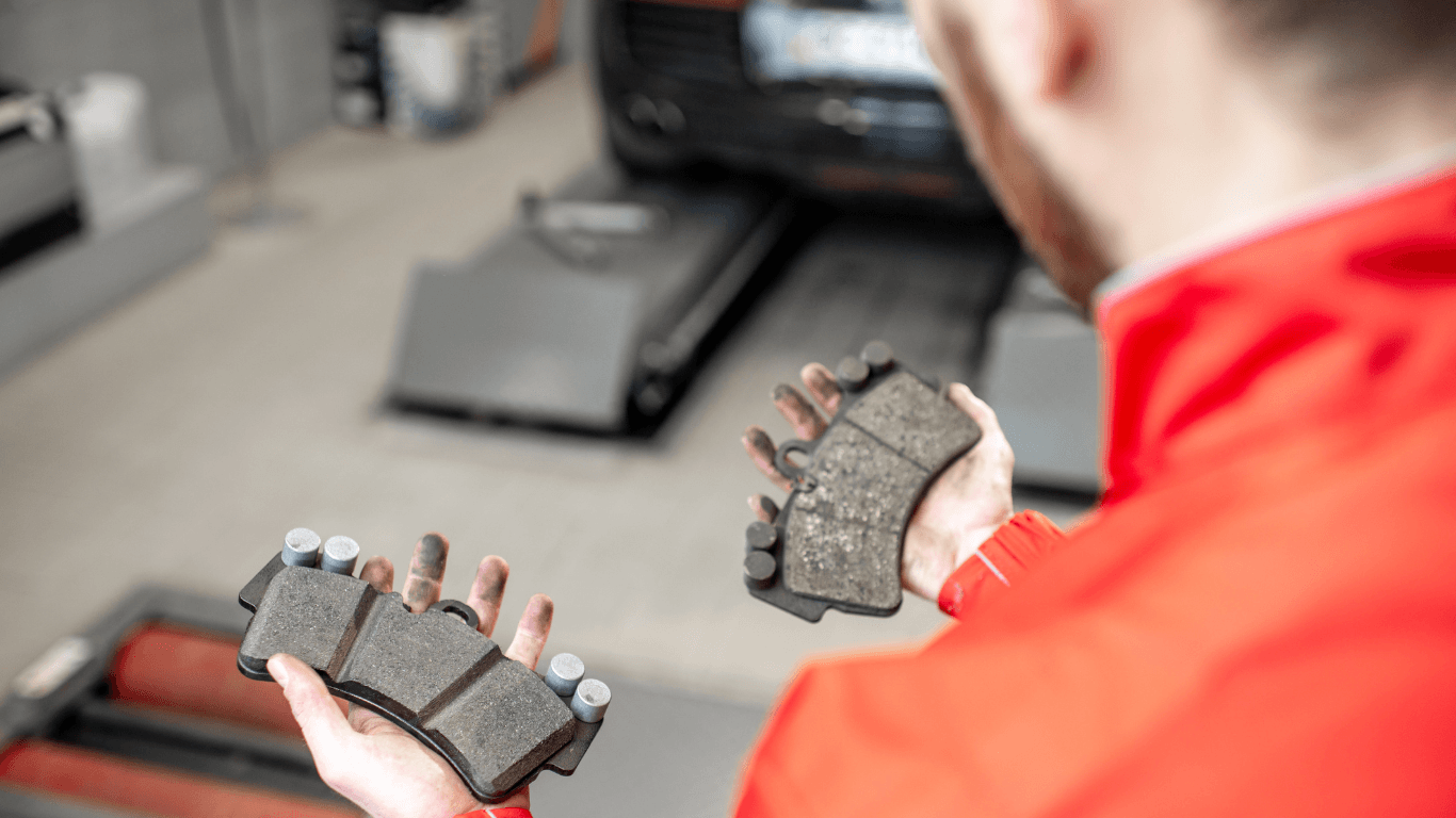 an auto repair technician holding brake pads
