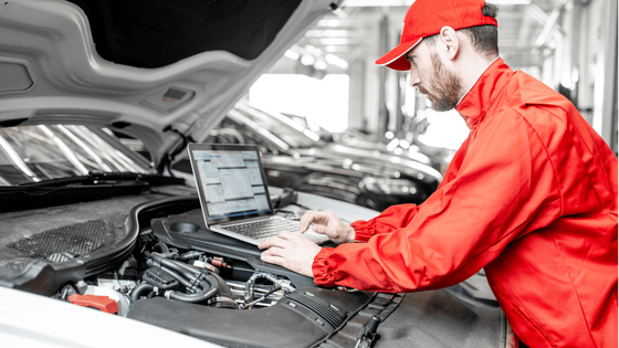 a mechanic doing a vehicle diagnostic with a laptop hooked up to the car