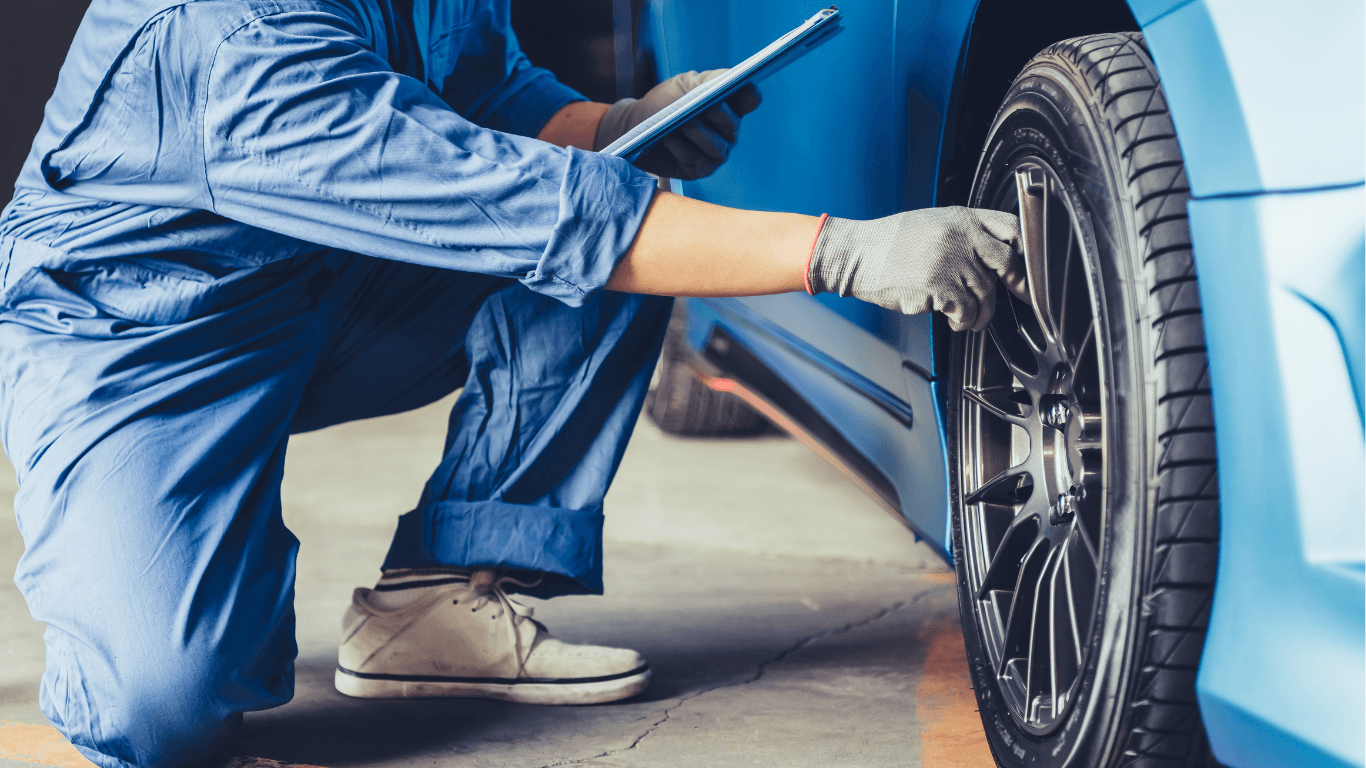 a mechanic examining the rims on the wheel of a car