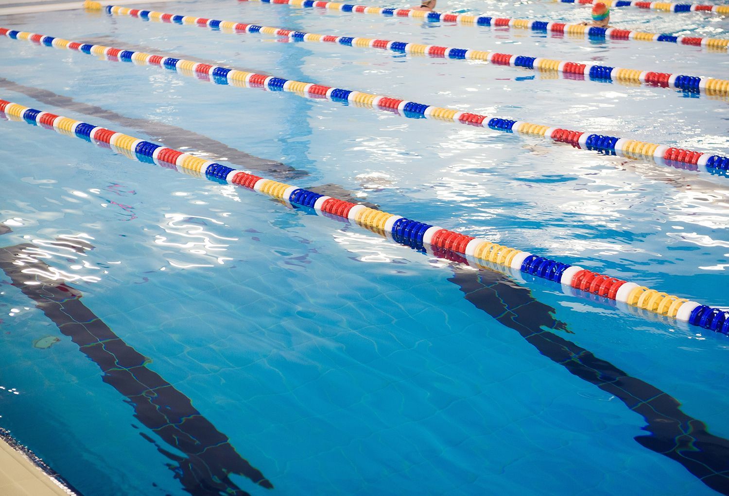Swimming pool lanes with blue water and red, yellow, and blue lane ropes