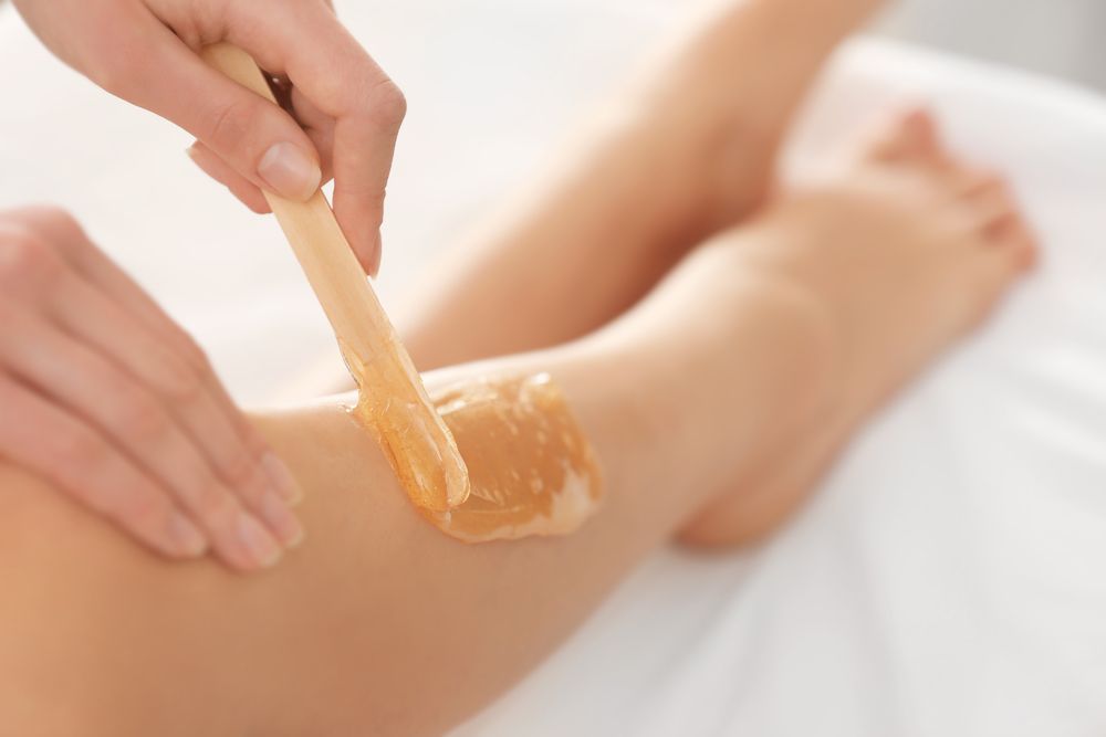 A woman is getting a waxing treatment on her leg.