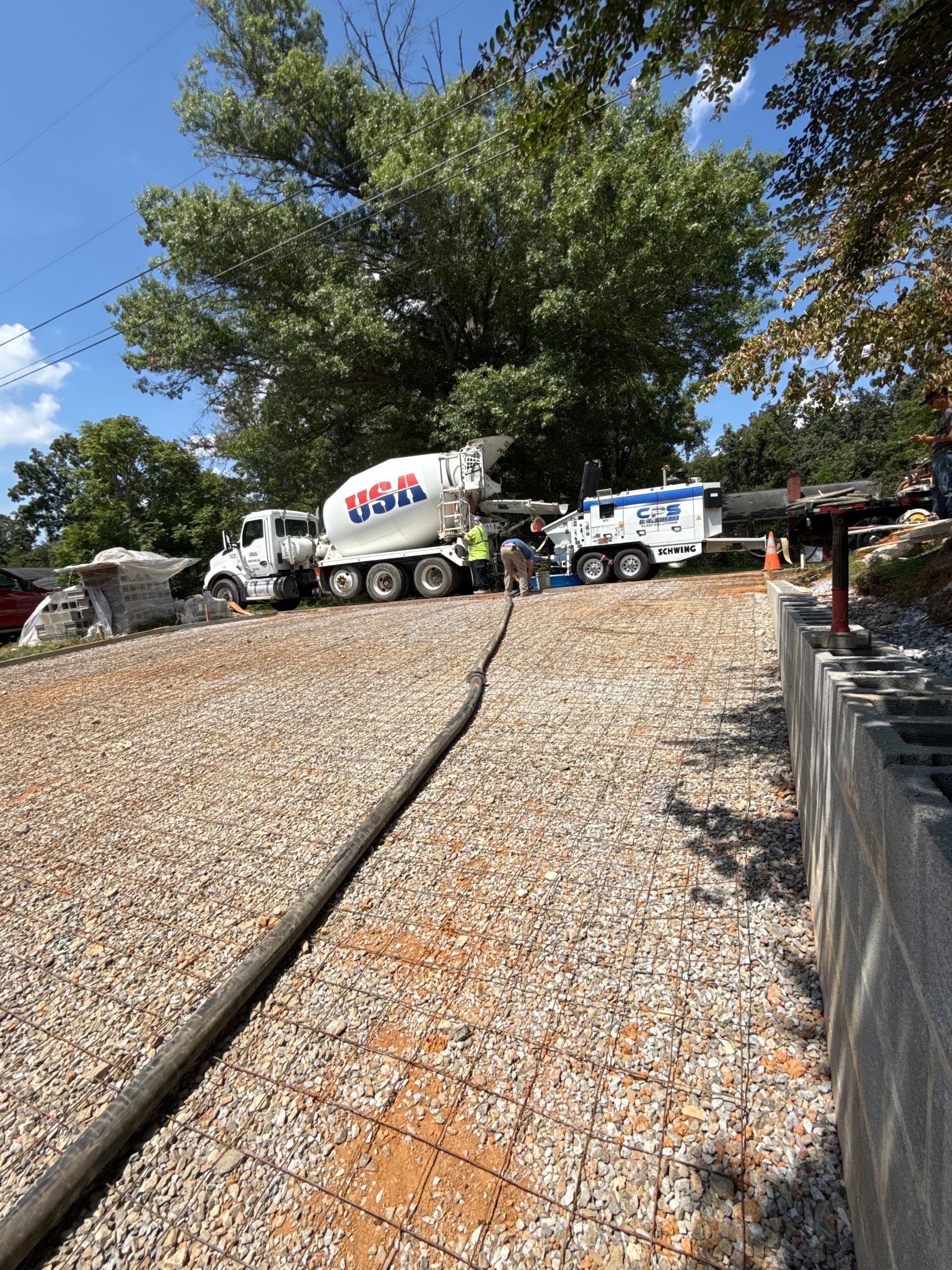 A group of construction workers are working on a concrete walkway.