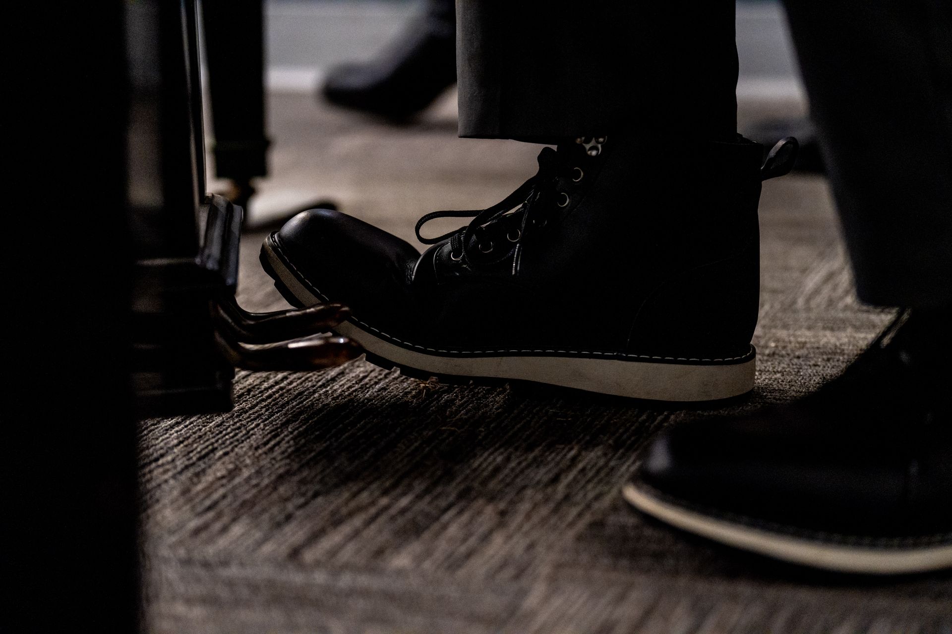 Black dress shoes on a carpeted floor in a dim indoor setting