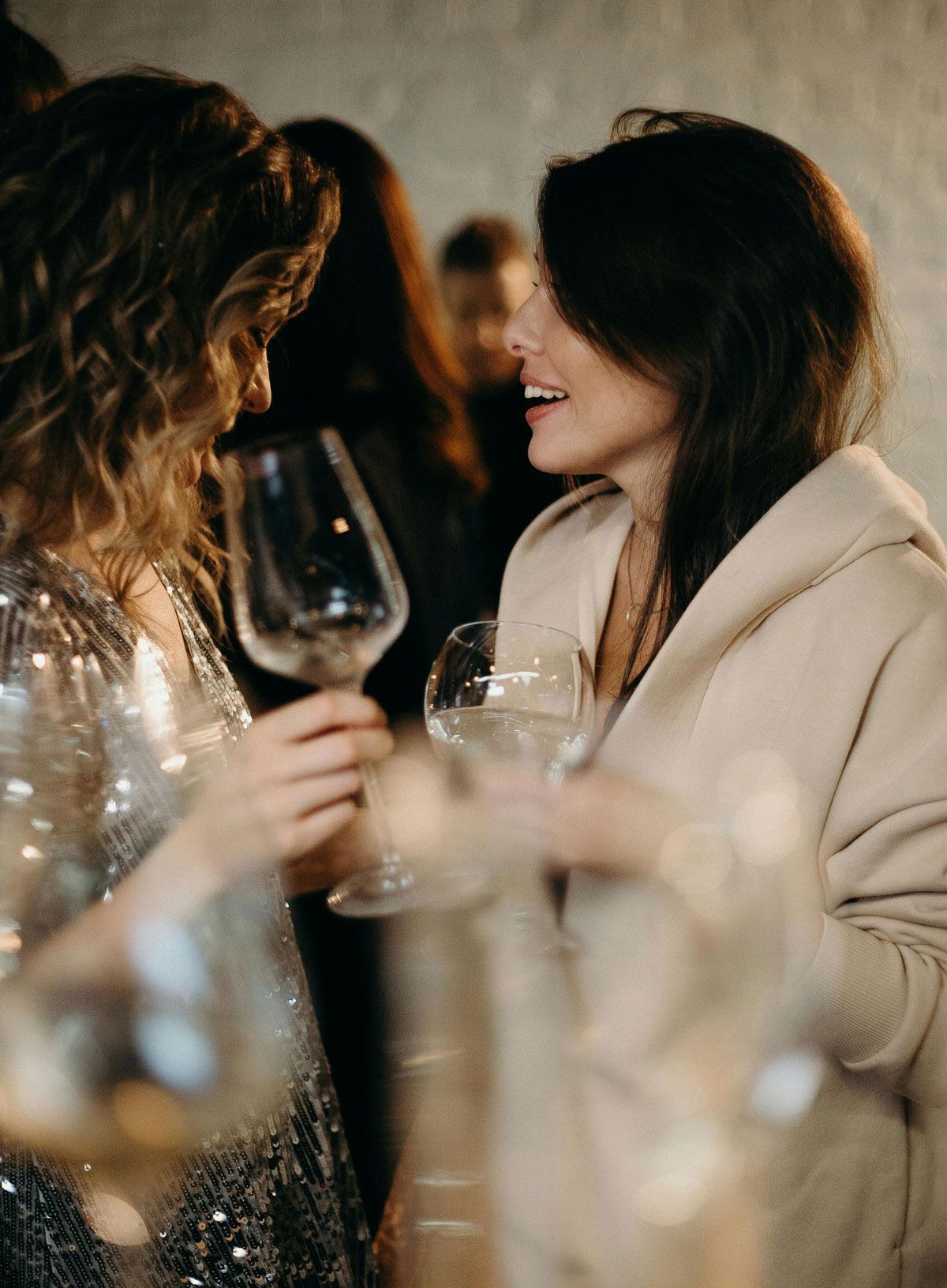 Two women chatting with wine glasses at a social gathering