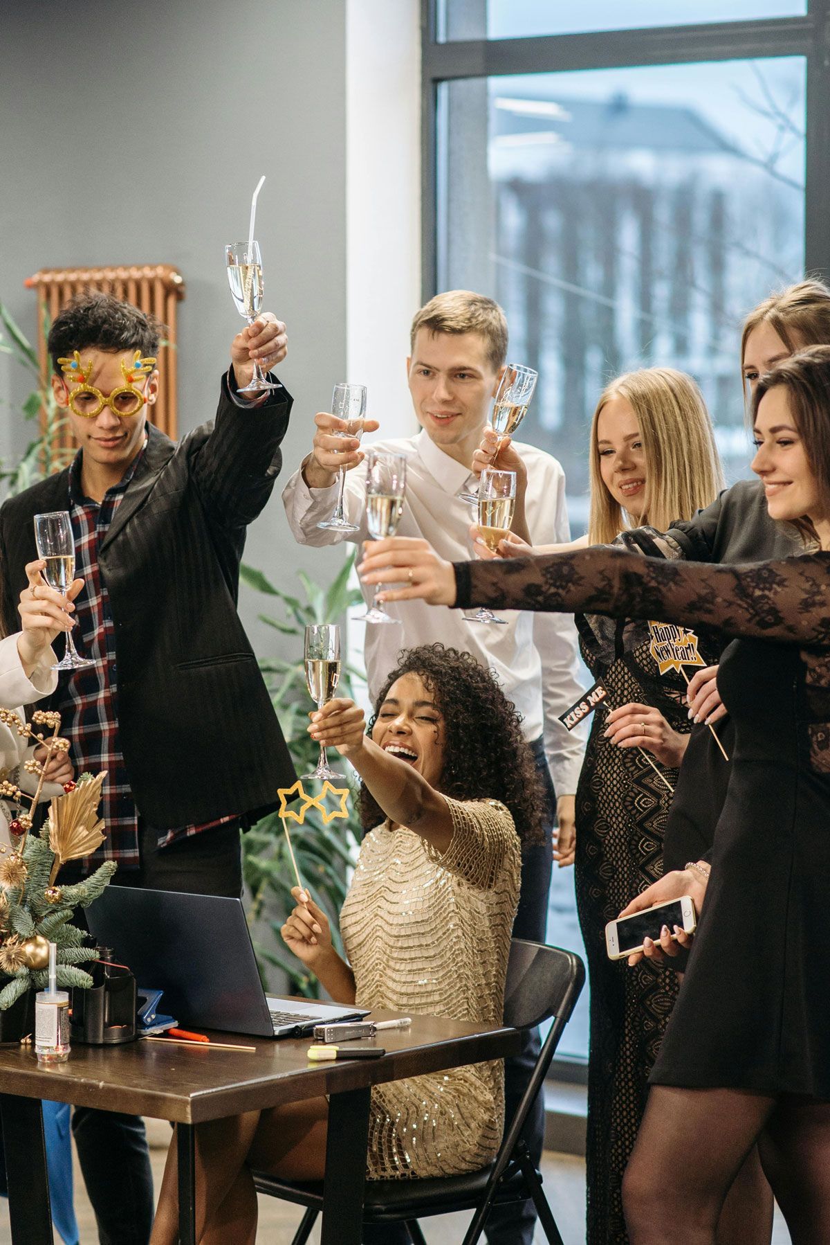 Friends toasting with champagne at a festive indoor gathering by a large window