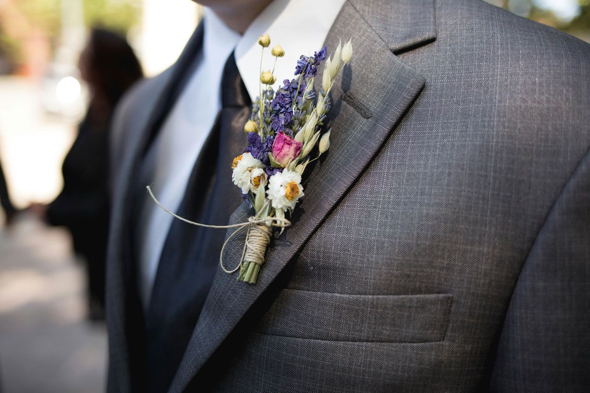 Gray suit jacket with a boutonniere of purple, white, and yellow flowers on the lapel